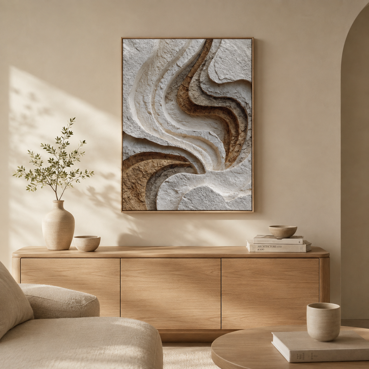 Relief textured canvas wall art displayed above a wooden sideboard in an organic modern living room with warm neutral decor
